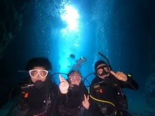 海中洞窟でピースサインをする3人のダイバー
